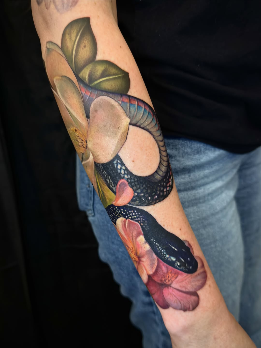 Snake and flowers watercolor tattoo on the forearm by Su Kang