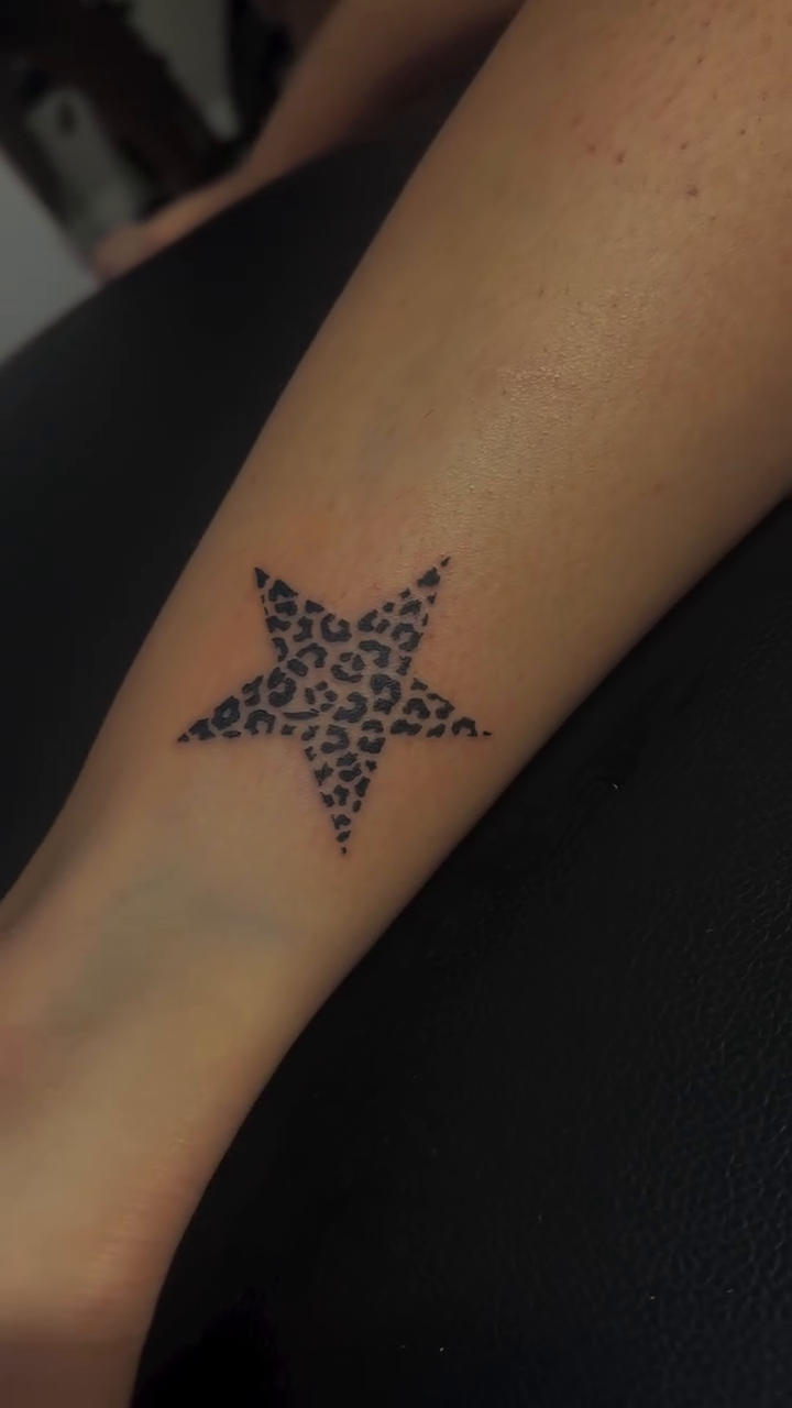 Leopard print star tattoo fine line tattoo on the forearm by Marly Quinn