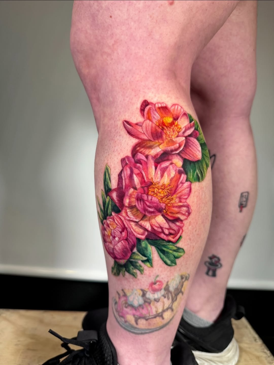 Pink flowers with green leaves neo-traditional tattoo on the calf by aria, Austin, Texas