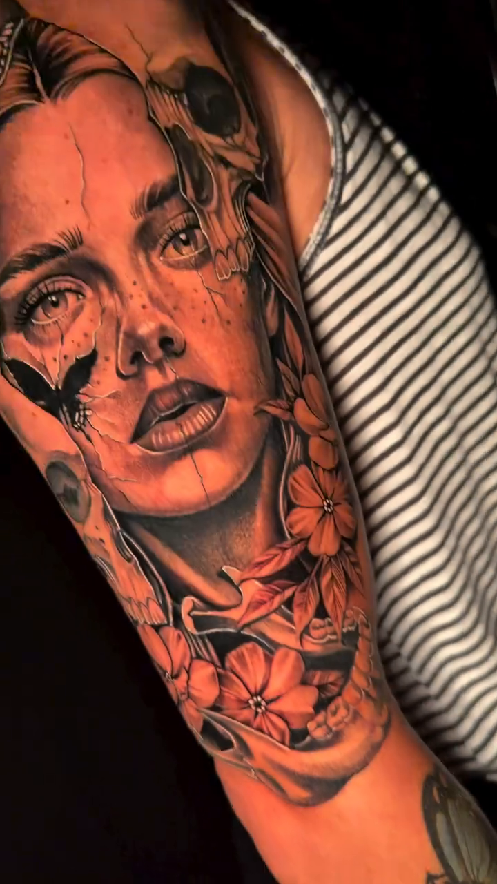 Woman's face with skull and flowers neo-traditional tattoo on the upper arm by Travis Sleeper