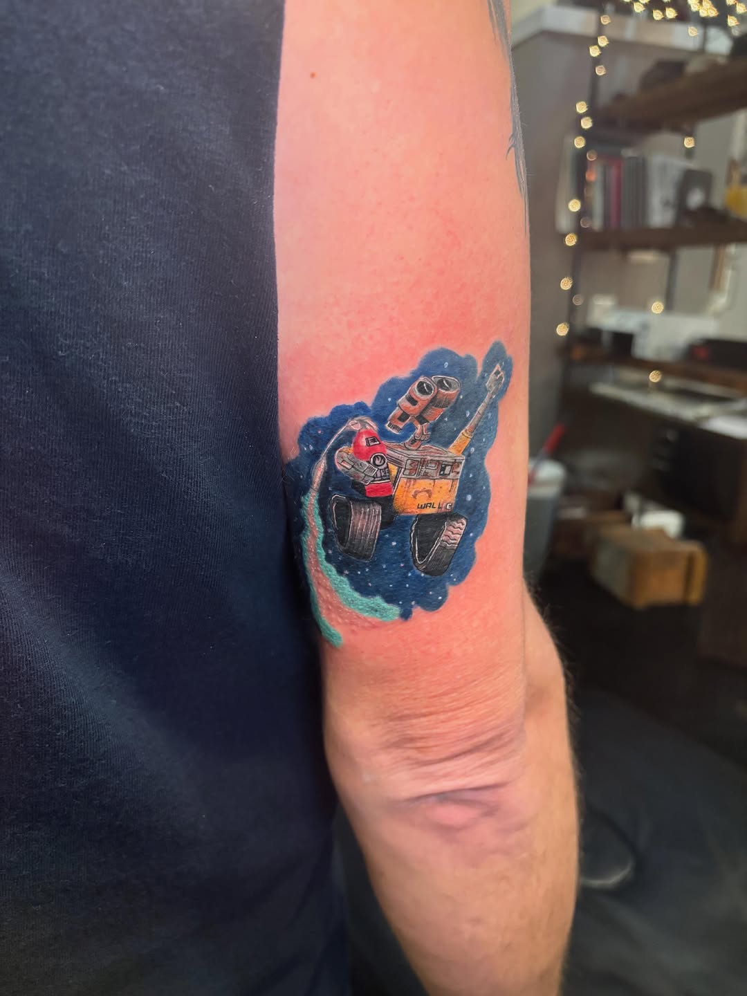 Wall-E robot in space tattoo on the forearm by Aubri Aunna