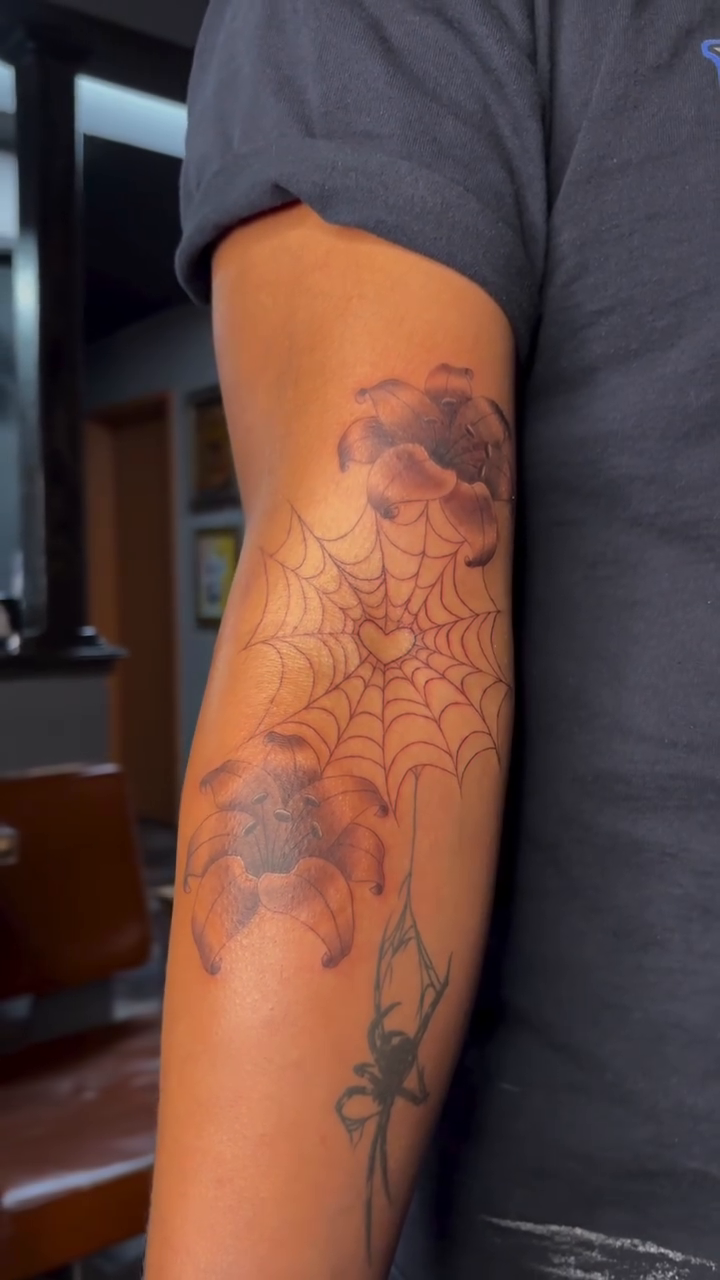 Spiderweb with spider and clouds fine line tattoo on the forearm by alana khounmeuang