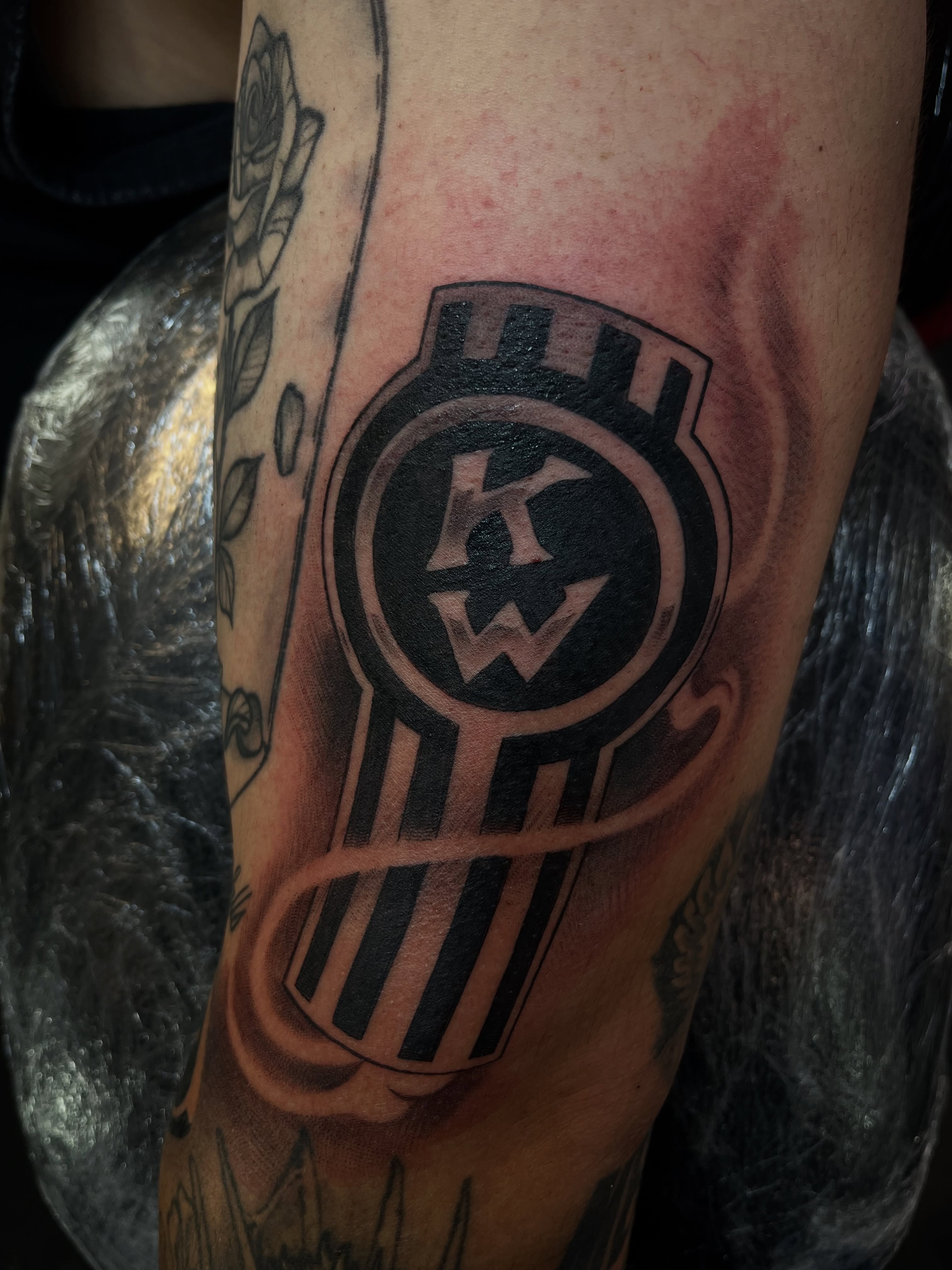 KW logo black and grey tattoo on the forearm by Kwete Tatuajes