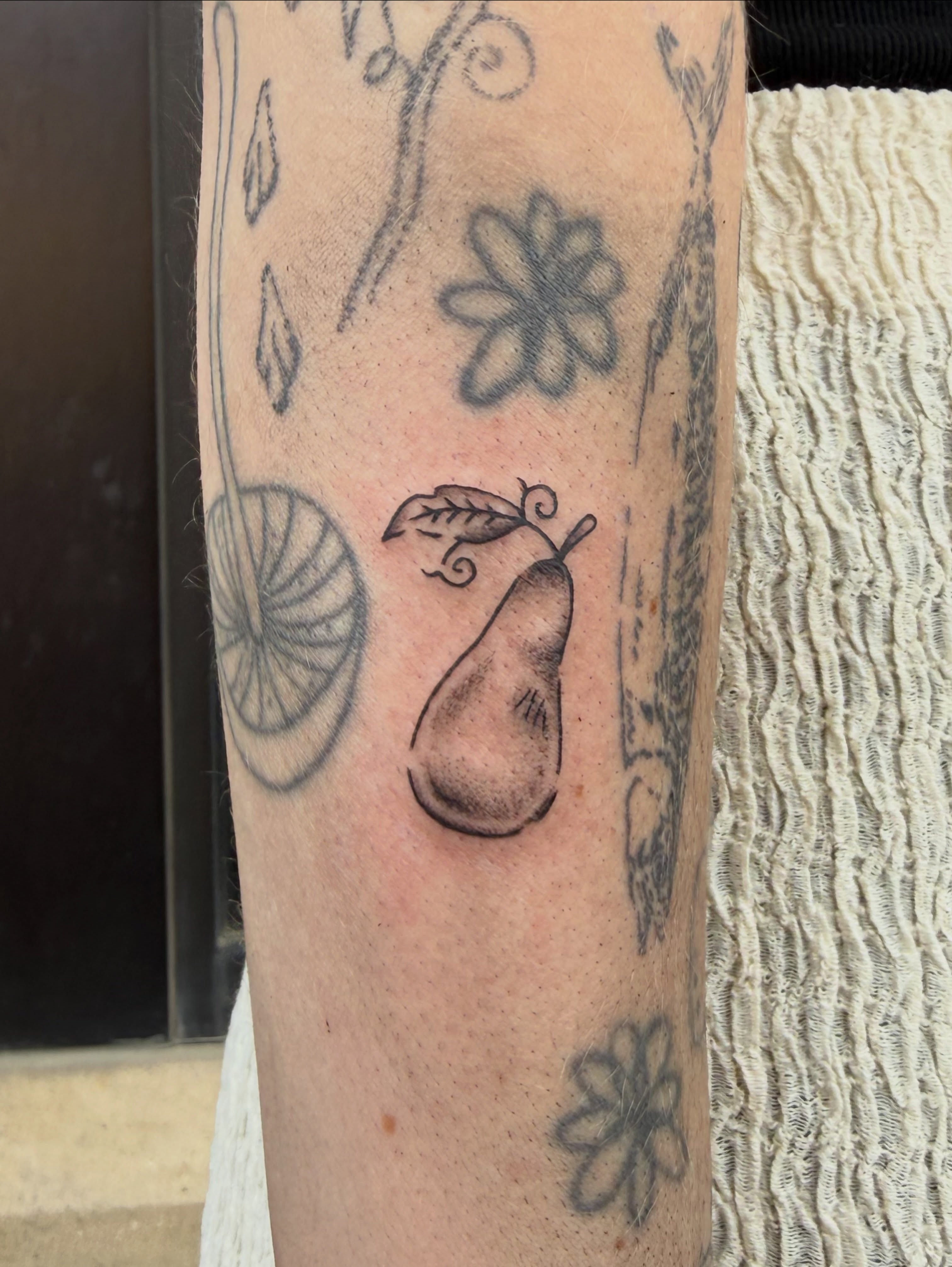 Pear black and grey tattoo on the forearm by Kieara West