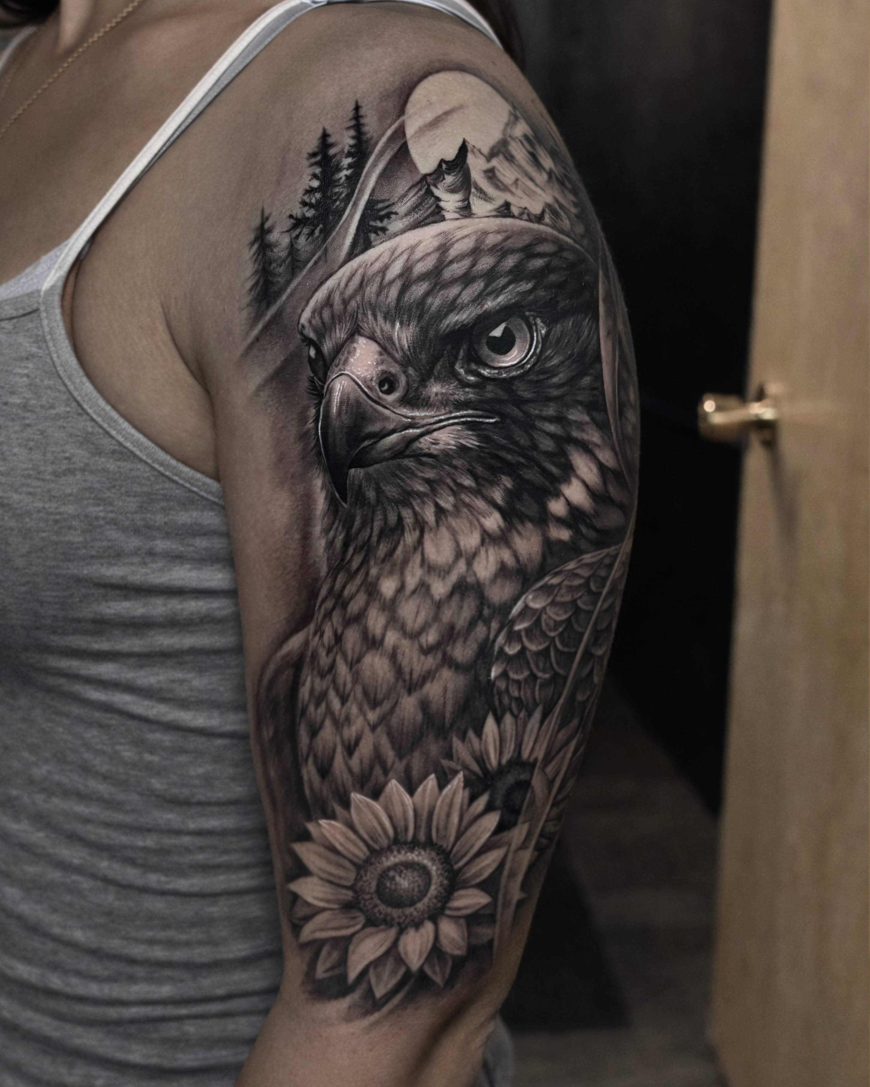 Hawk and sunflower realism tattoo on the upper arm by Bob Lindell Tattoos