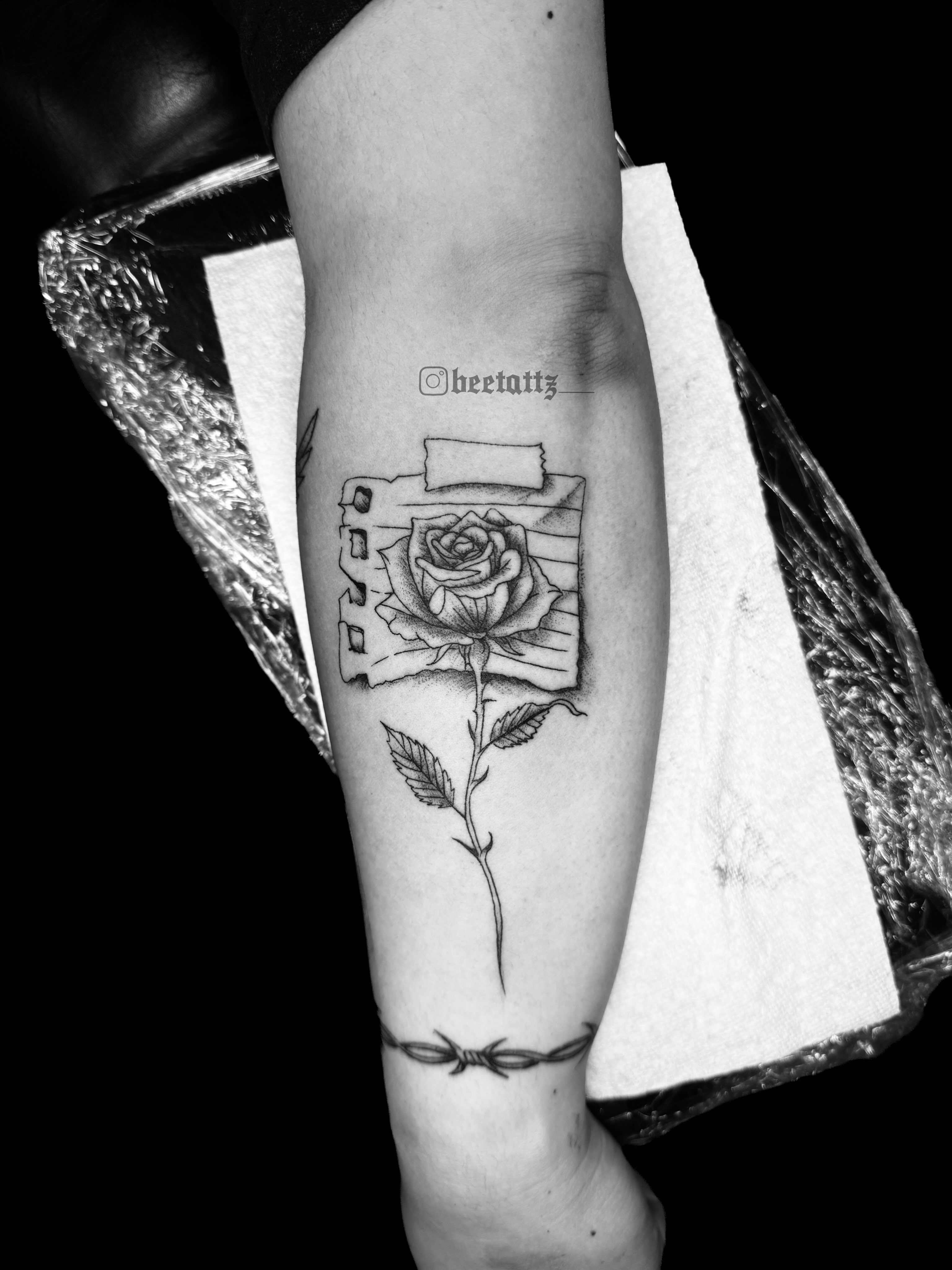 Rose and camera black and grey tattoo on the forearm by Brinkley McGill