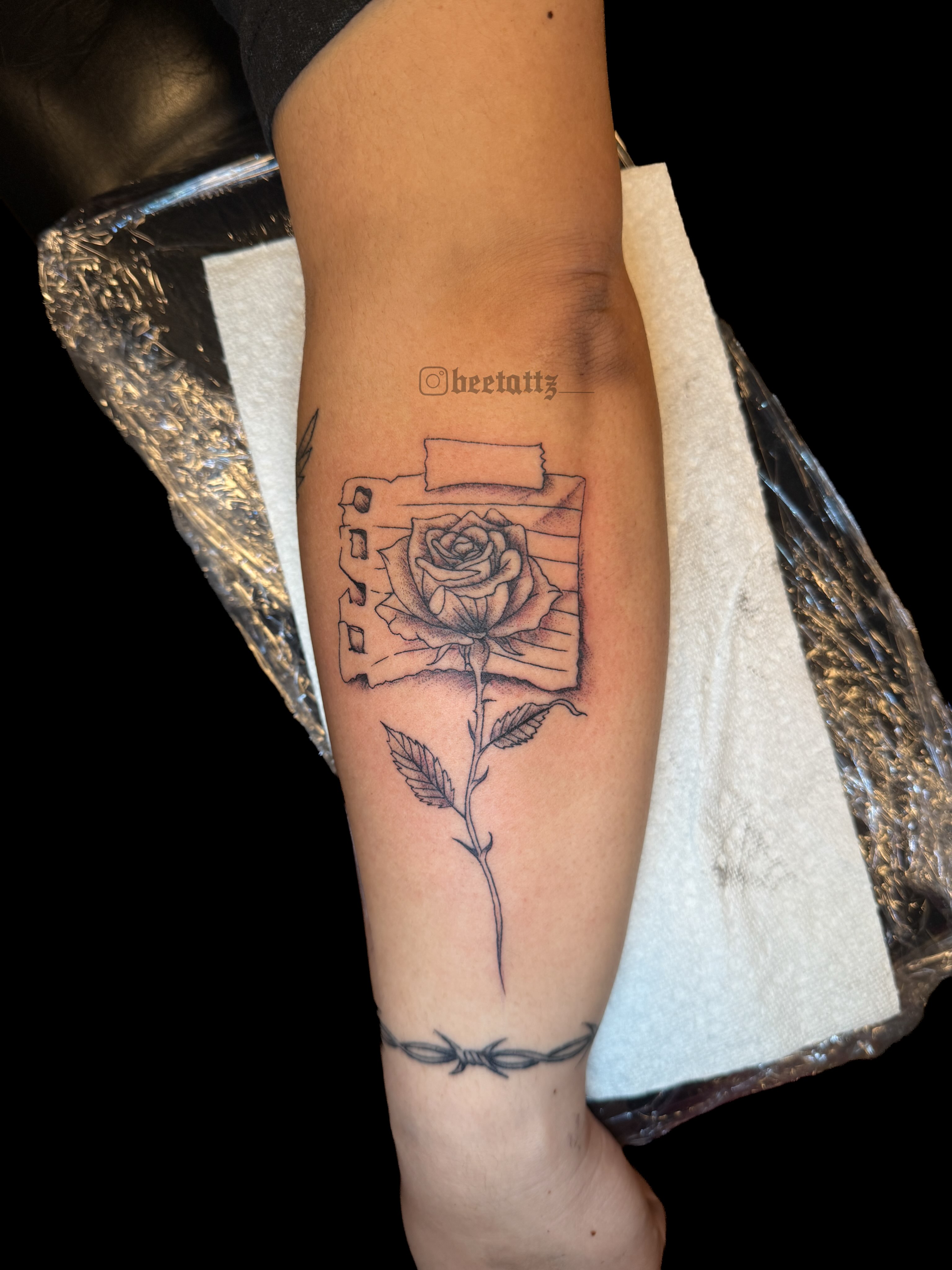 Rose and camera black and grey tattoo on the forearm by Brinkley McGill