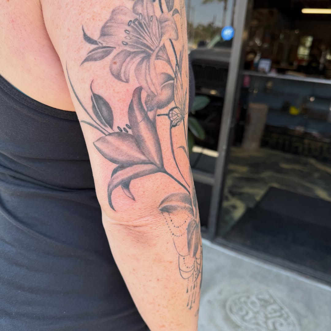 Lily black and grey tattoo on the forearm by Faith Lopez