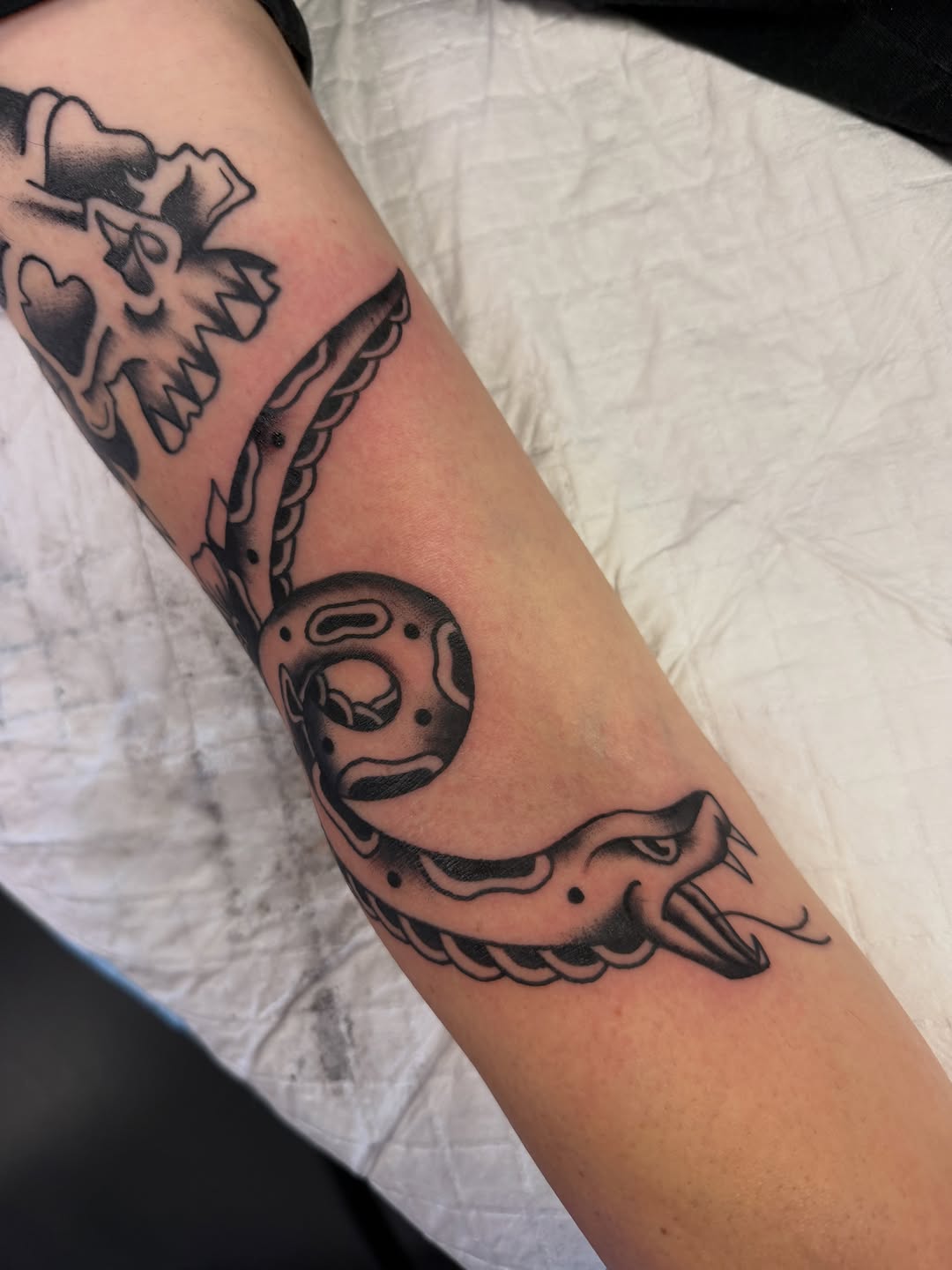 Snake and skull American traditional tattoo on the forearm by Nick Tumminello