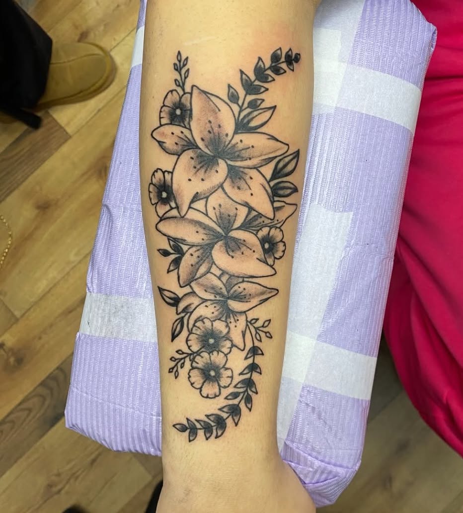 Lilies and flowers black and grey tattoo on the forearm by Destinee DeFriece