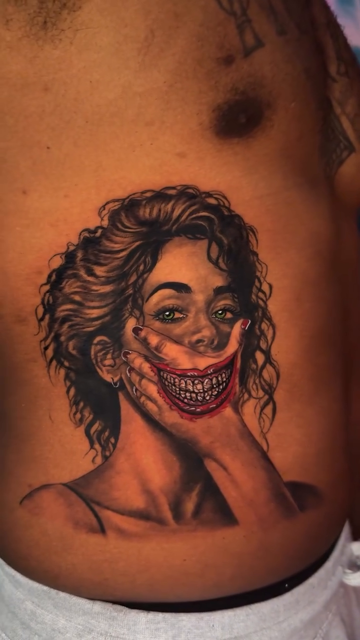 Woman with Joker-like smile realism tattoo on the chest by Tony Hernandez, Chicago, Illinois