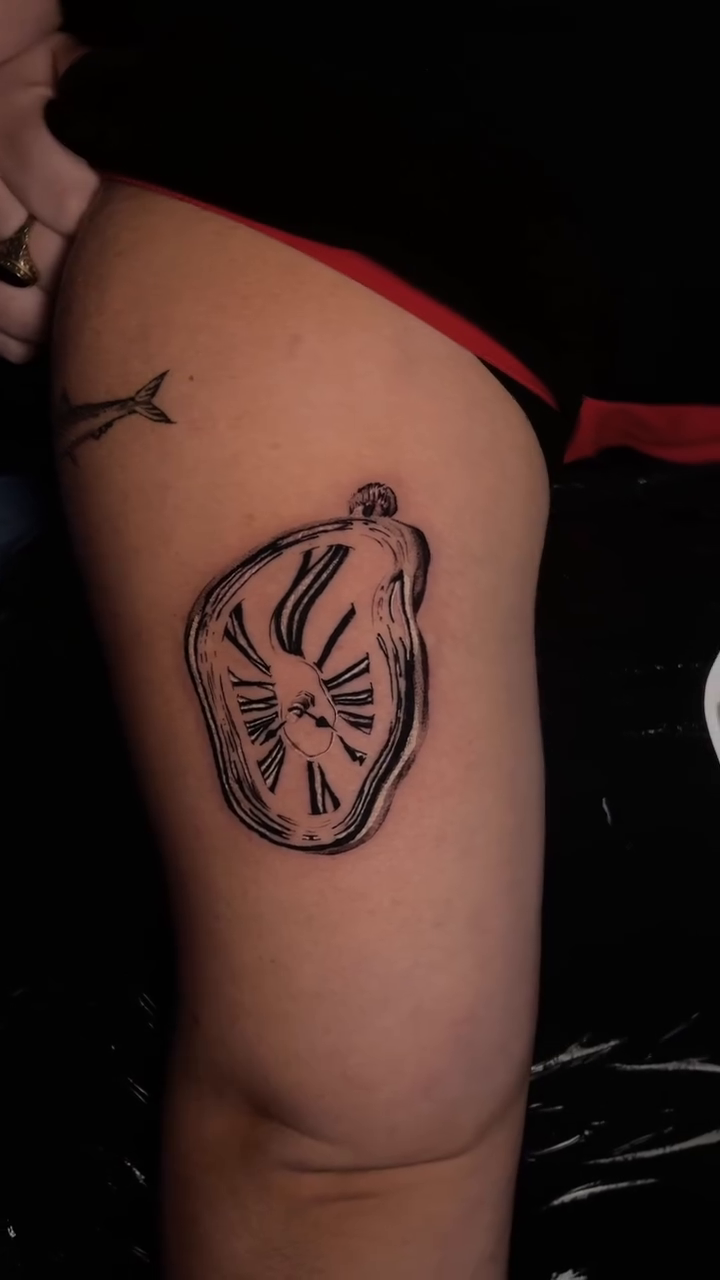 Dali's melting clock surrealism tattoo on the thigh by clarissa