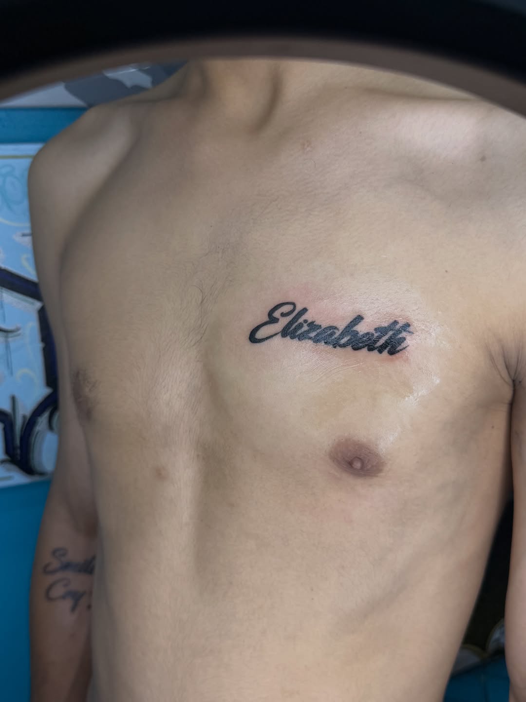 Elizabeth script lettering tattoo on the chest by ⠀Greave