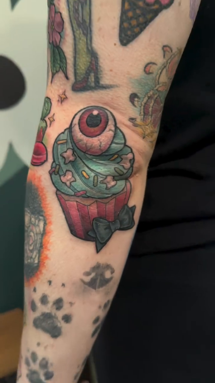 Cupcake with an eyeball American traditional tattoo on the upper arm by Katie Hutchins, Dayton, Ohio