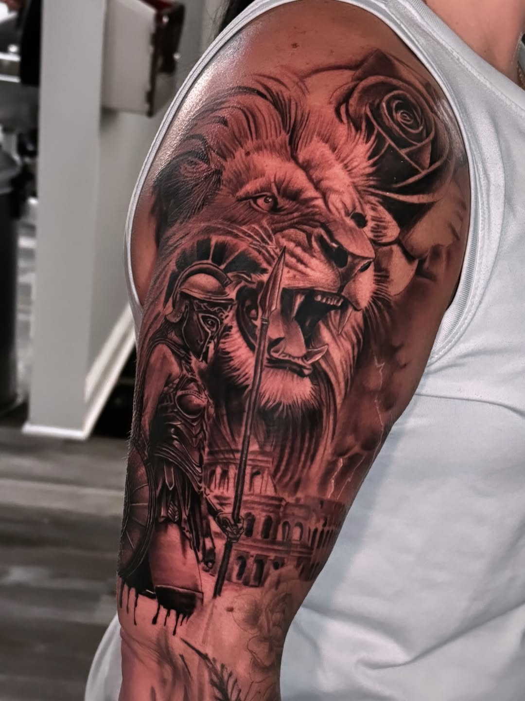 Lion, roman soldier, colosseum, rose realism tattoo on the upper arm by Miguel Garcia