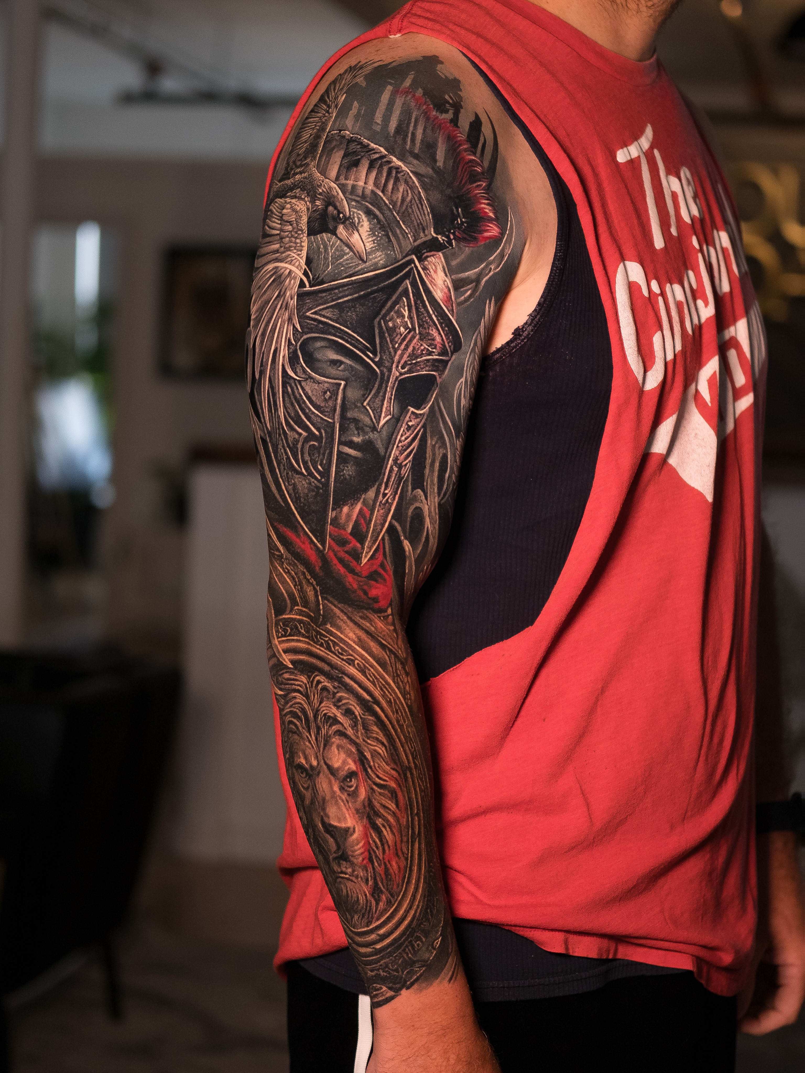 Spartan helmet, raven, and lion Japanese tattoo on the upper arm by Christopher Powell