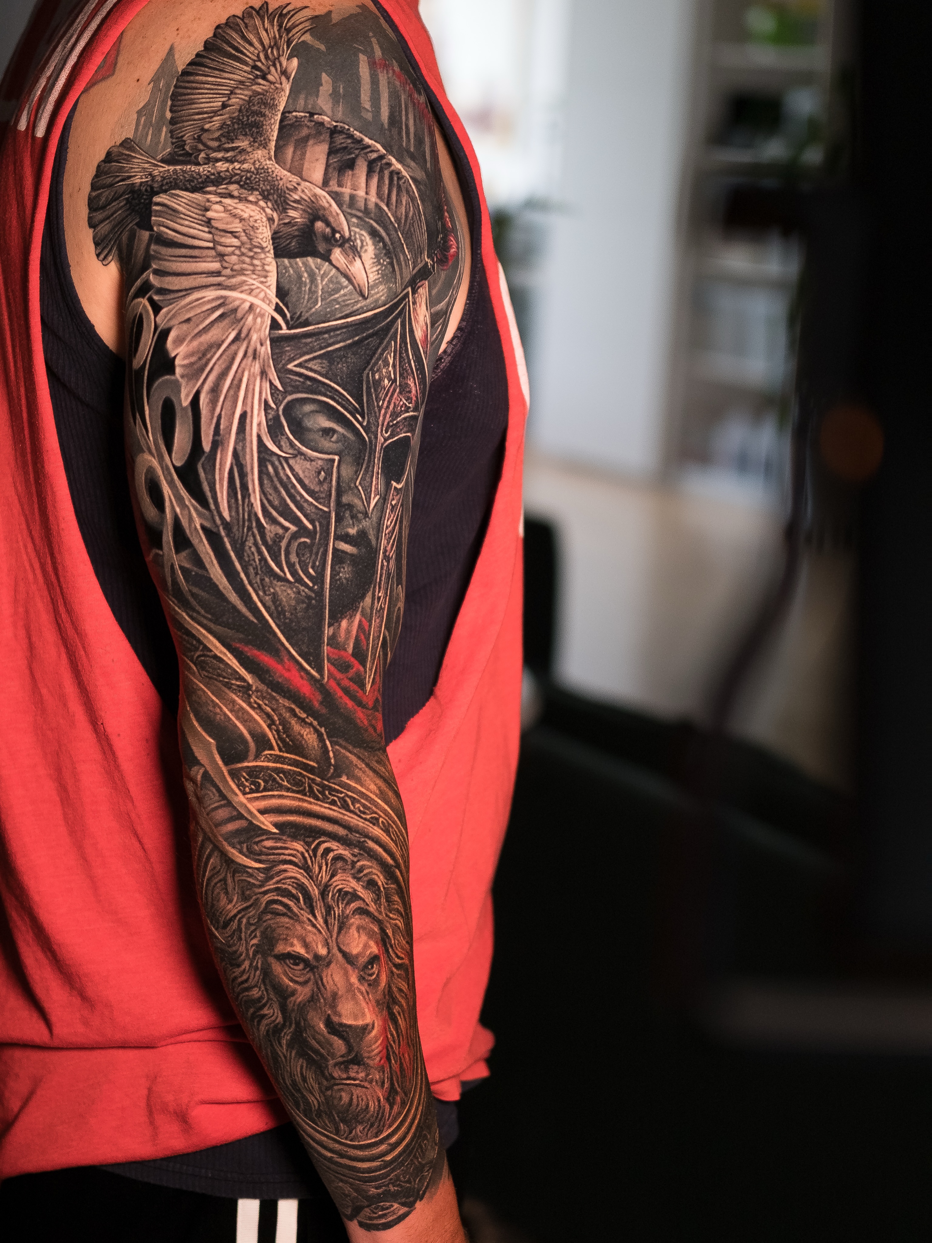 Raven, warrior helmet, and lion Japanese tattoo on the upper arm by Christopher Powell