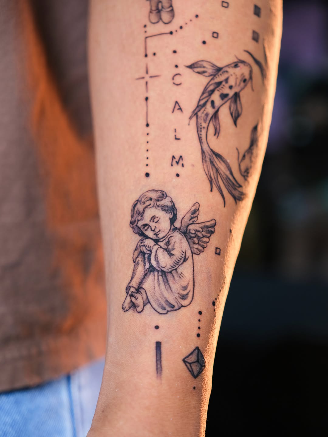 Cherub and koi fish realism tattoo on the forearm by Tattoo Miami π