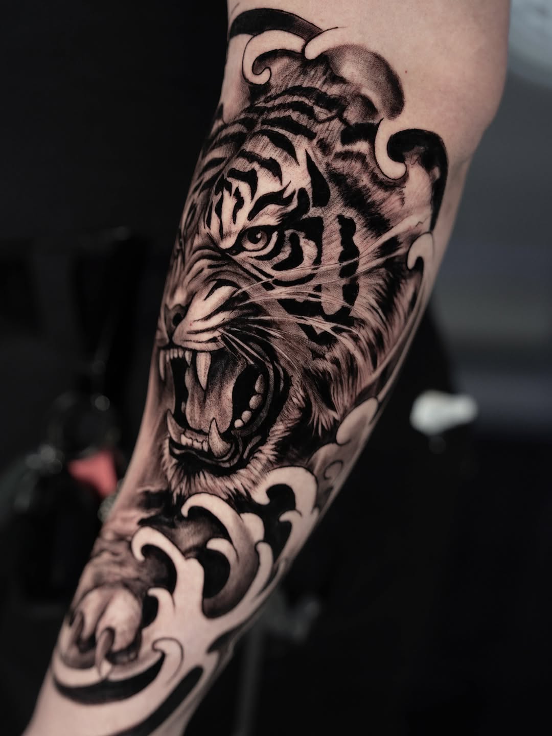 Tiger head with waves realism tattoo on the forearm by Idalia Pulido