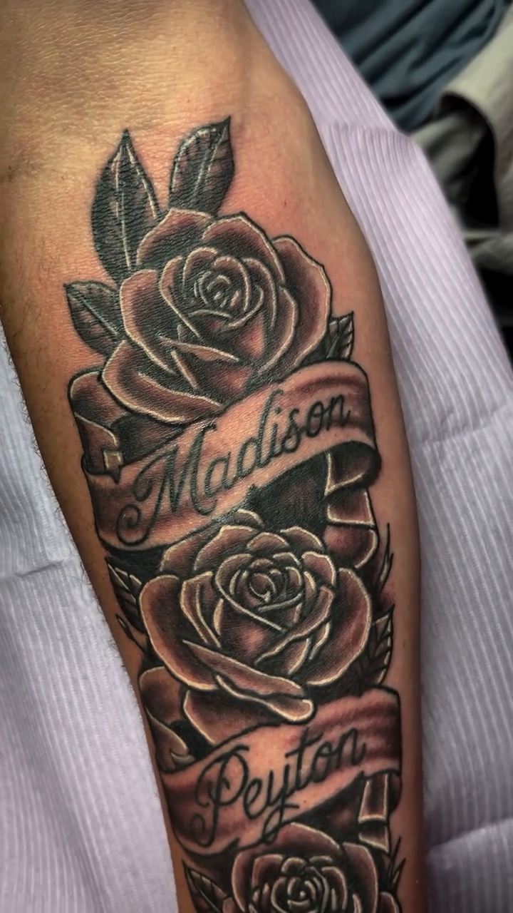 Roses with names on banners Chicano tattoo on the forearm by Anthony Guido