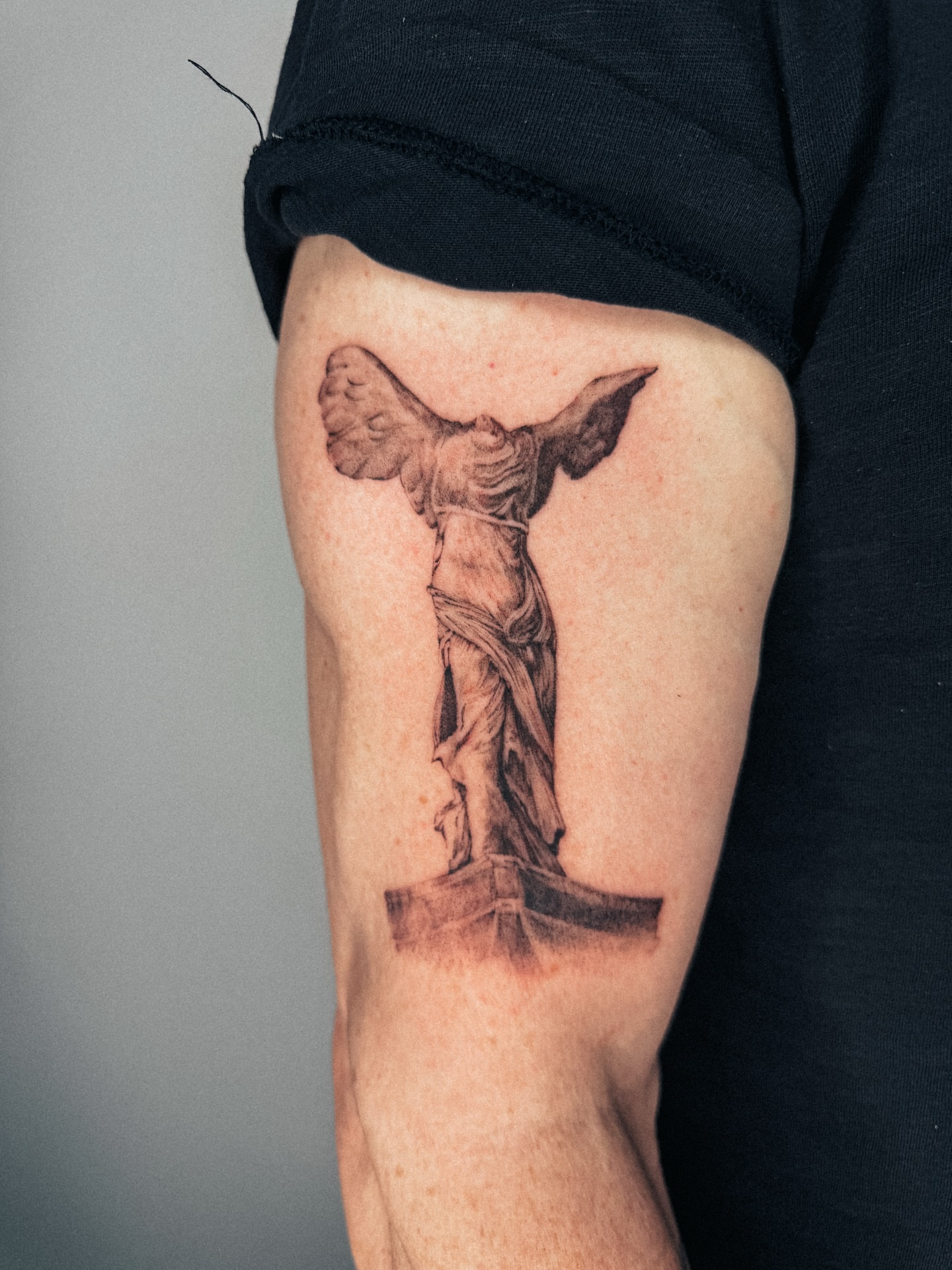 Winged statue black and grey tattoo on the forearm by Emma- Los Angeles Tattoo Artist