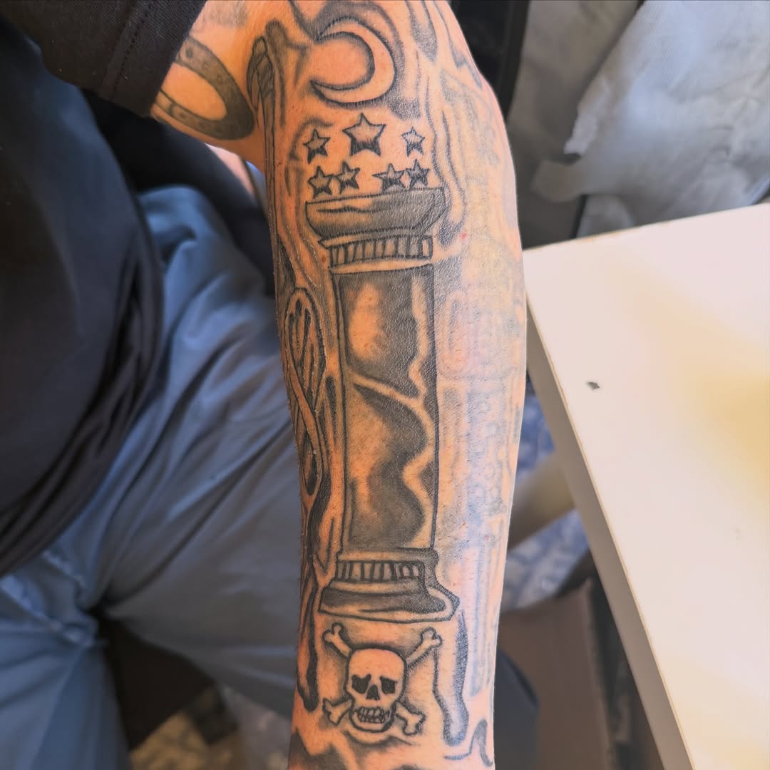 Column with skull and crossbones realism tattoo on the forearm by Addison Bruce