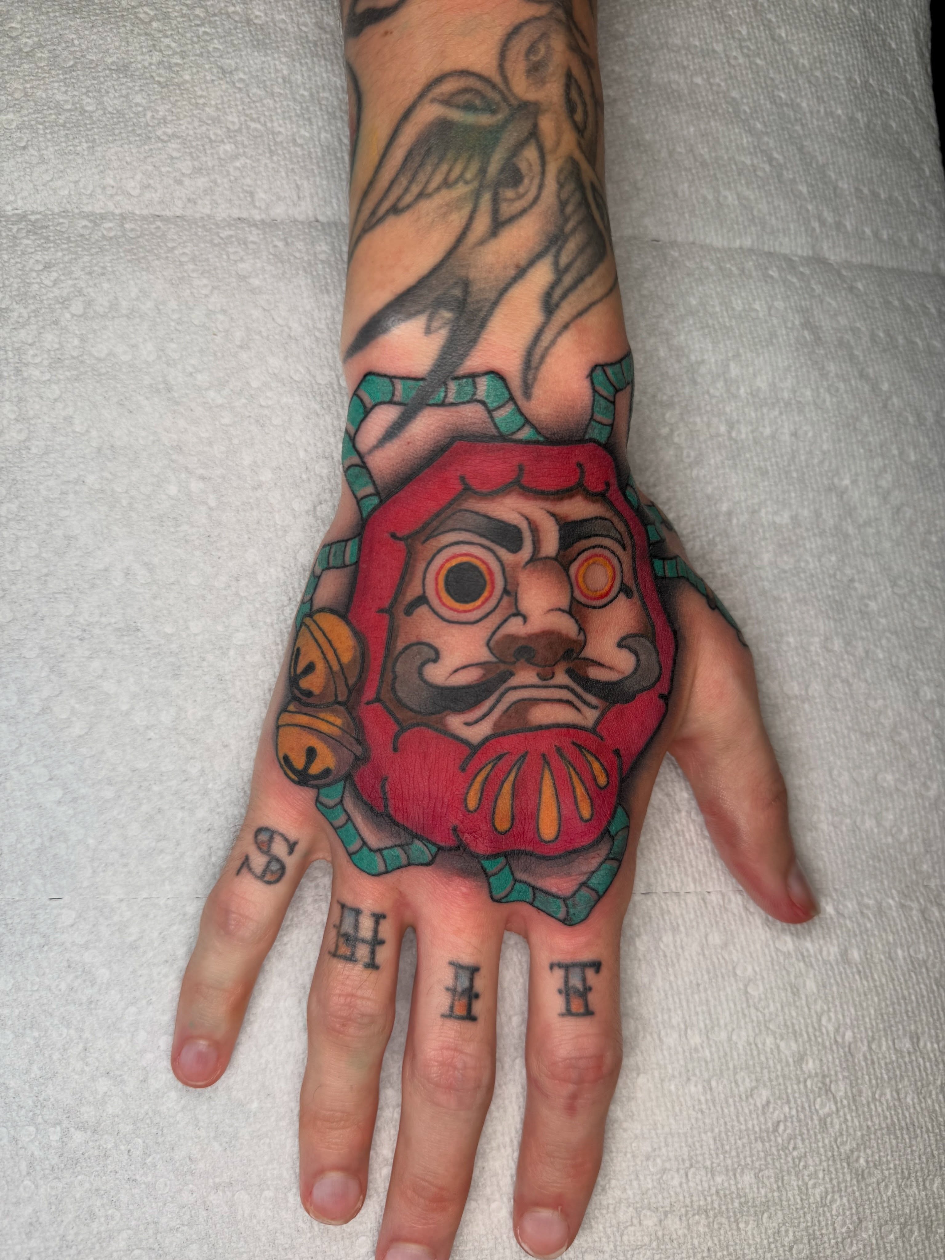Mask American traditional tattoo on the hand by Casket