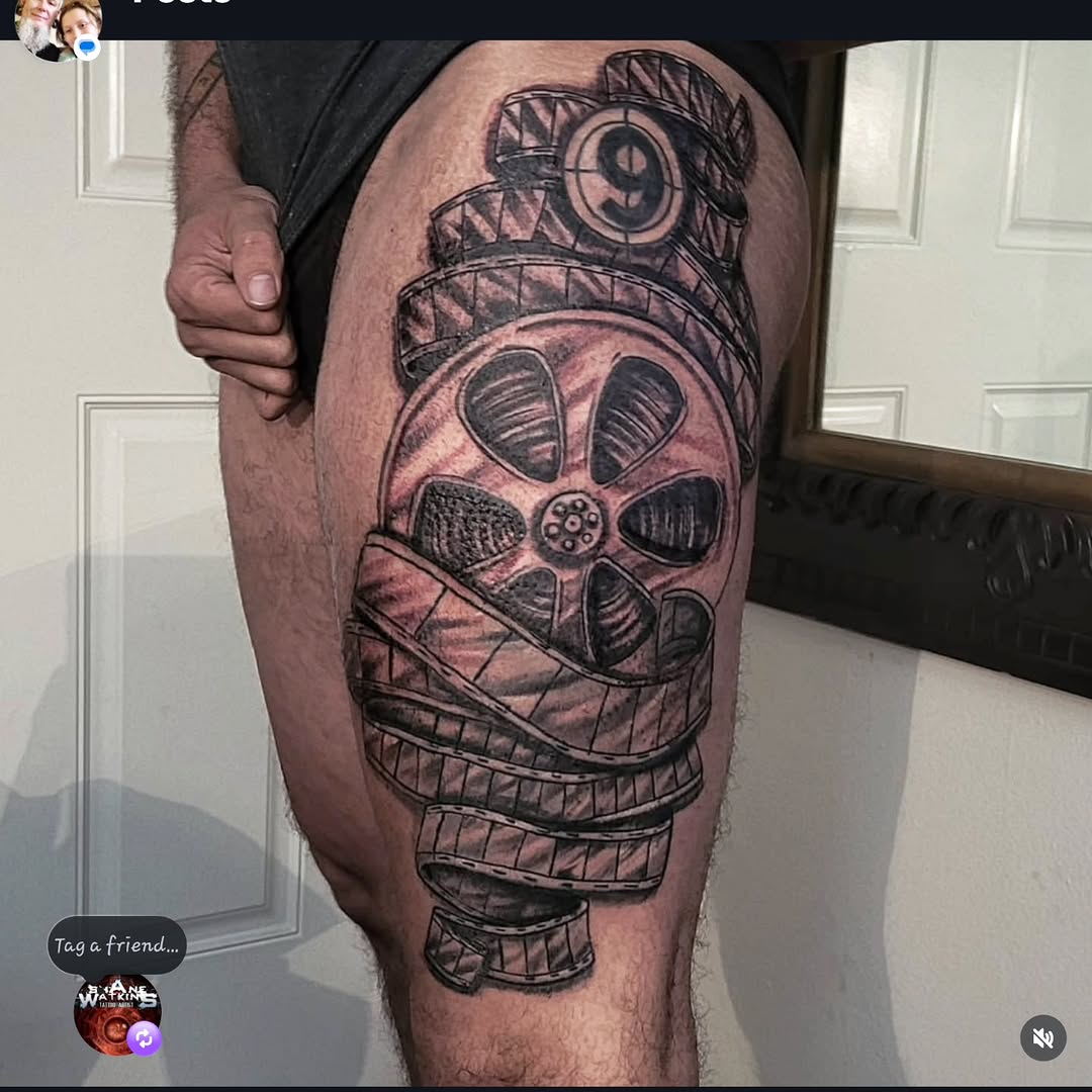 Film reel and strip surrealism tattoo on the thigh by Shane Watkins