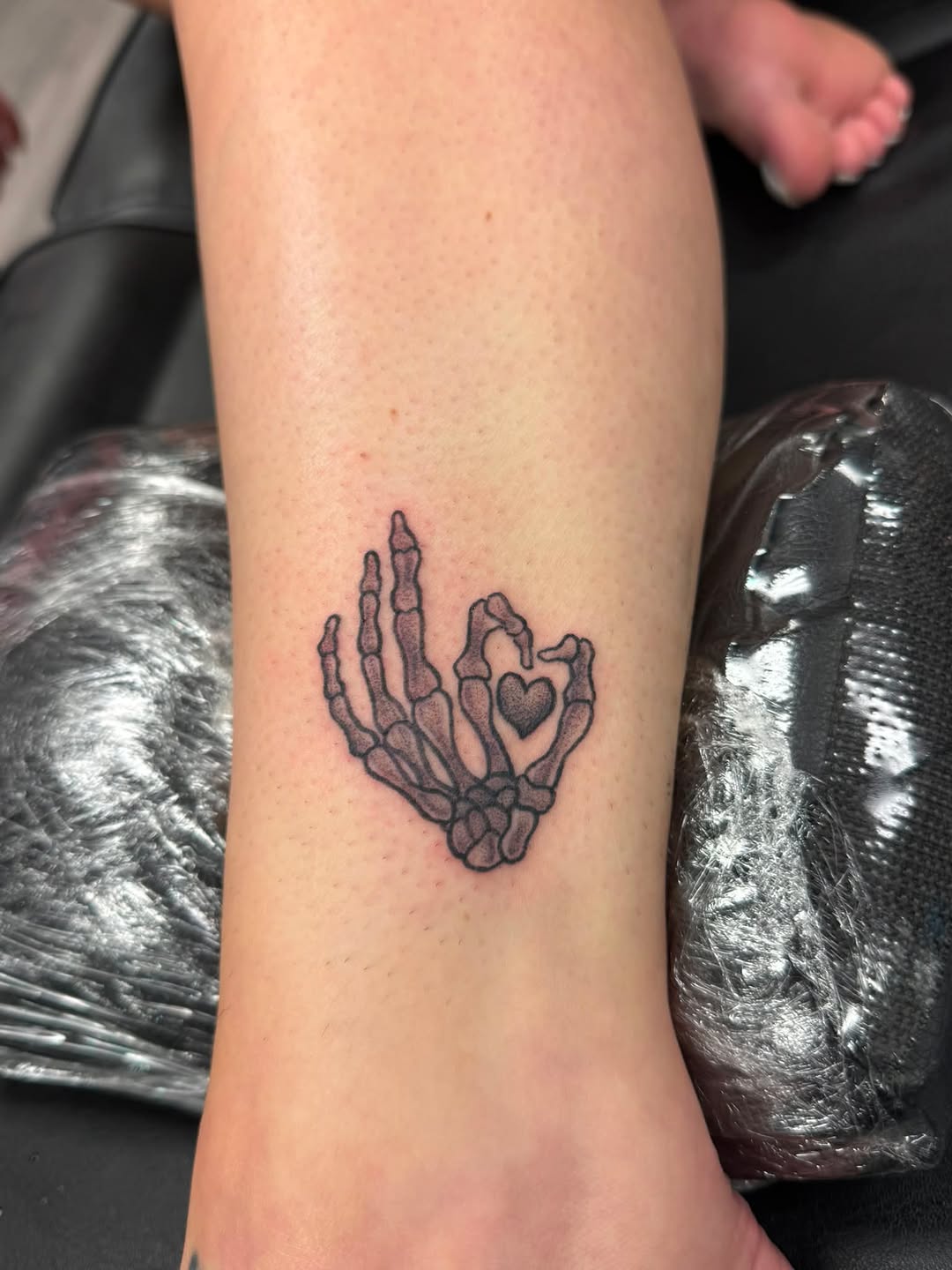 Skeleton hand forming heart dotwork tattoo on the forearm by Israel Jacob Woehler