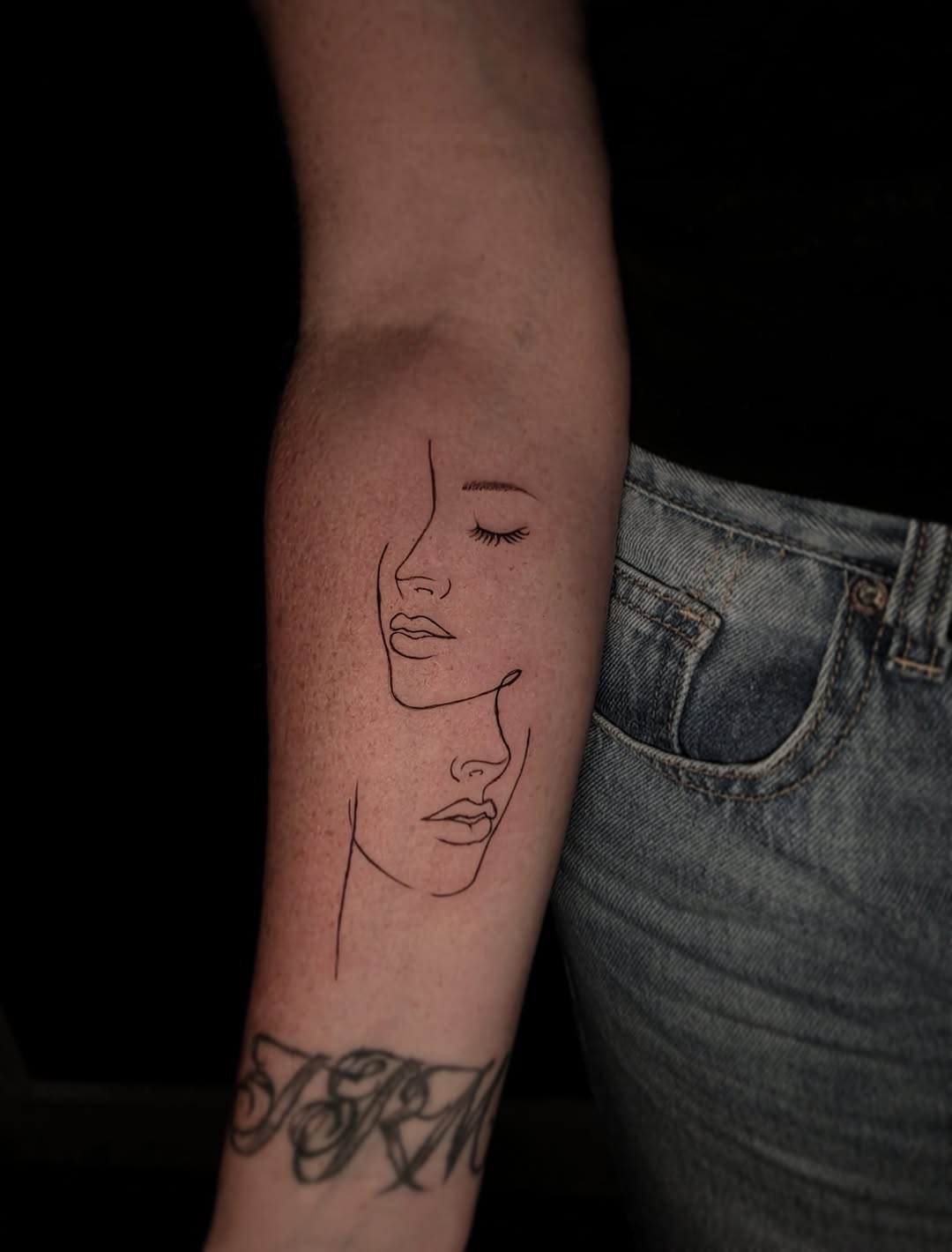 Two faces in profile surrealism tattoo on the forearm by Scar