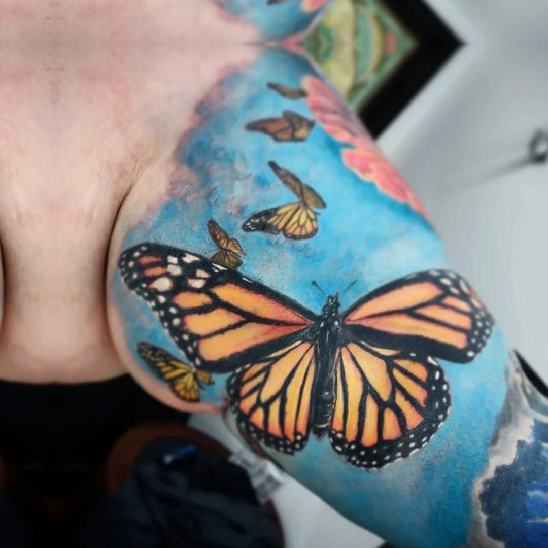 Monarch butterflies with blue background watercolor tattoo on the shoulder by Katelyn Bartoletti