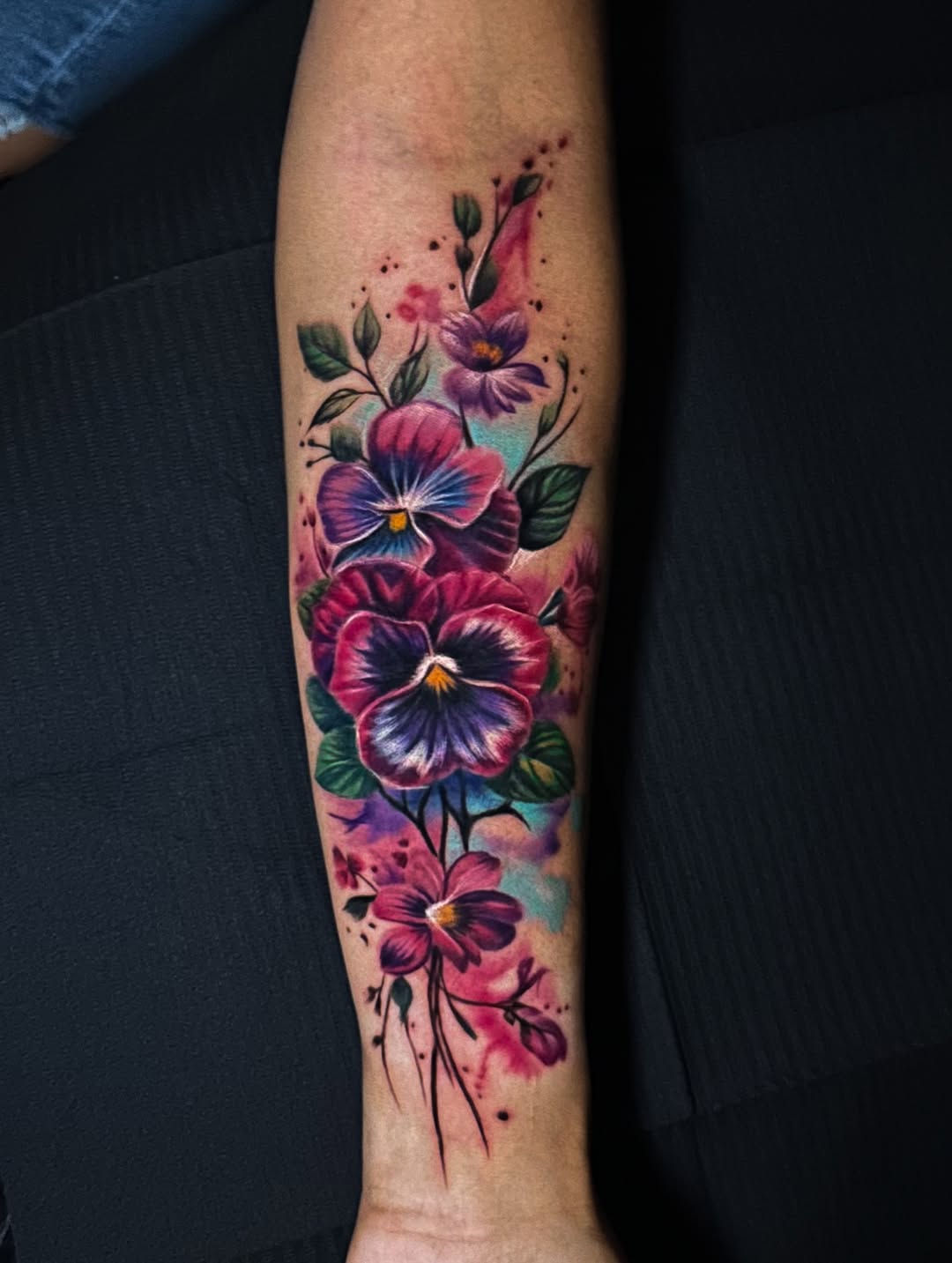 Pansies and watercolor splashes watercolor tattoo on the forearm by Omar Sheriff Herrera