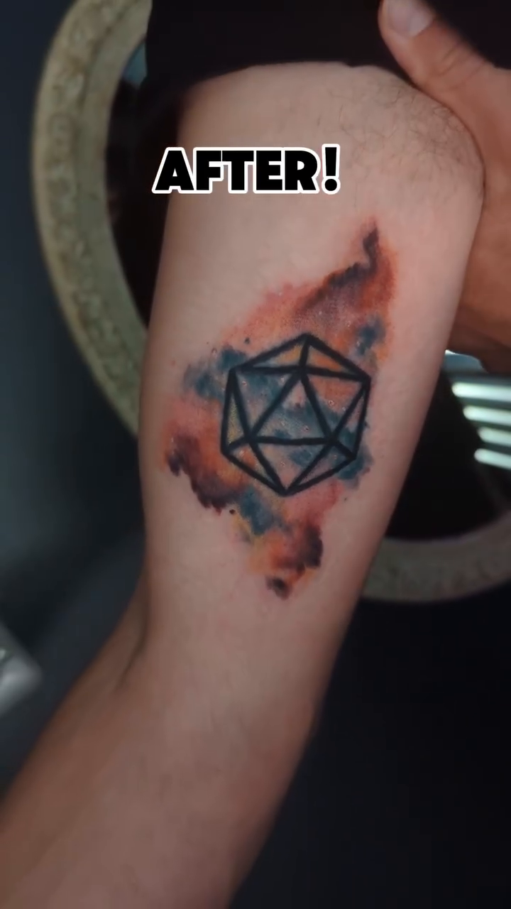 D20 die with watercolor background geometric tattoo on the forearm by Narnia Gallagher