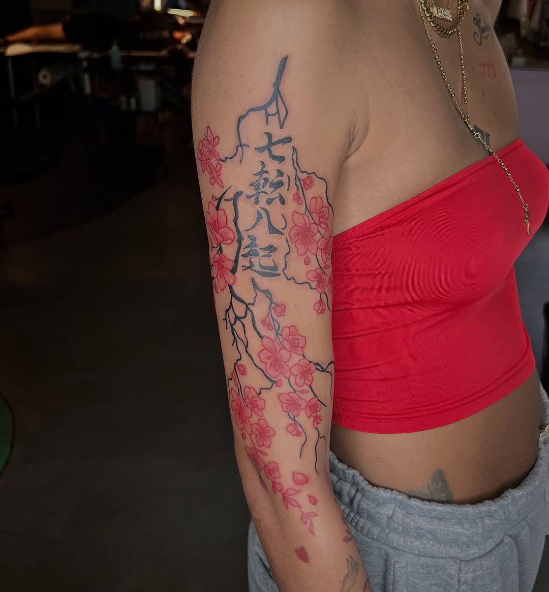 Cherry blossoms with calligraphy Japanese tattoo on the upper arm by Tattoo (Réaliste), Toulouse, Occitanie