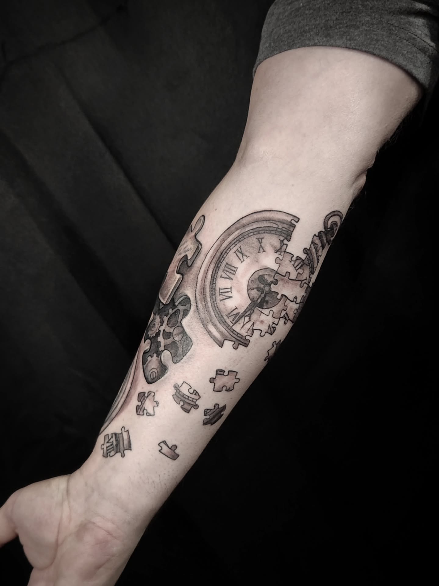 Clock and puzzle pieces black and grey tattoo on the forearm by Arthur Whitney Shail