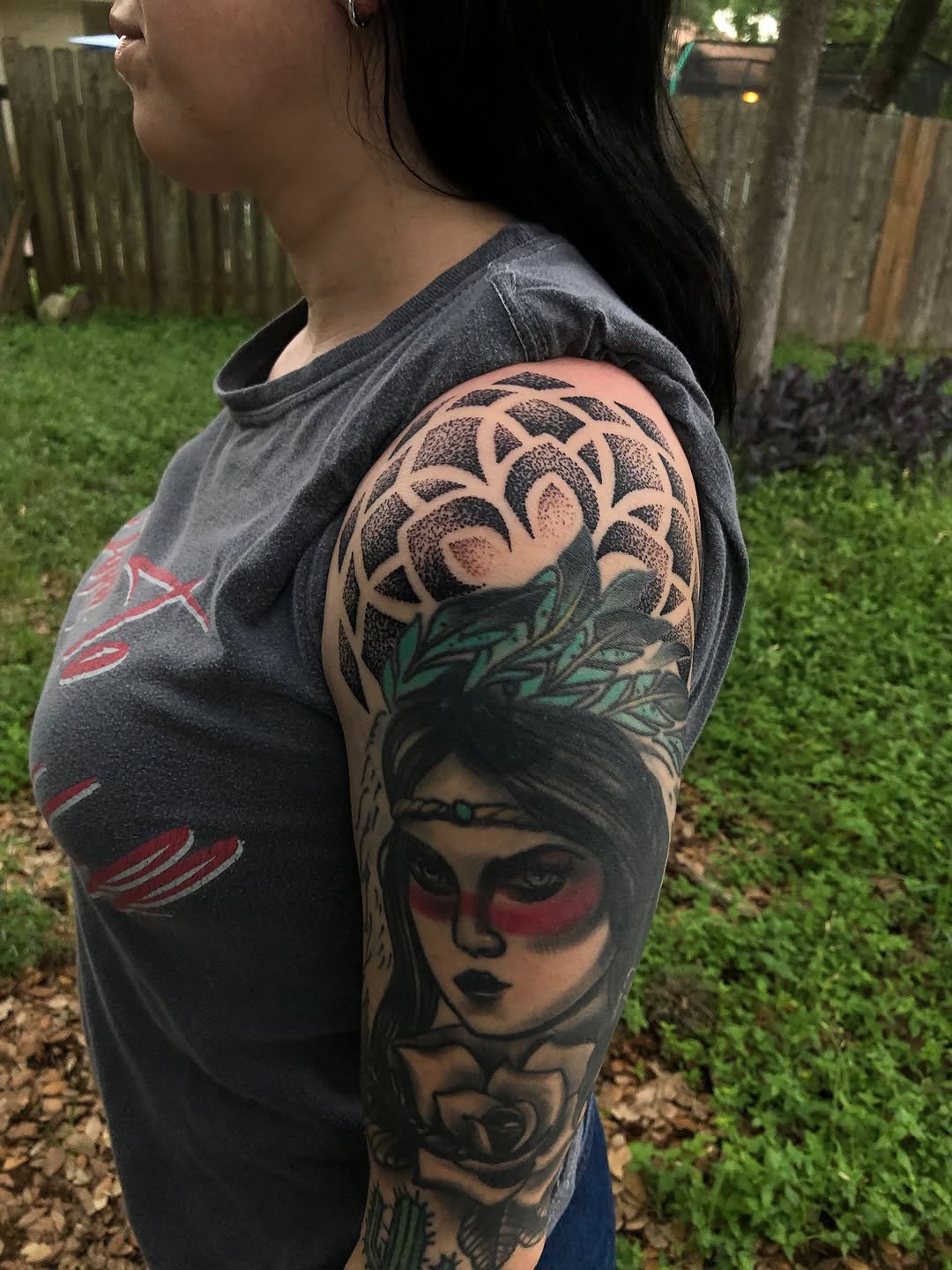 Woman with feather headdress and rose ornamental tattoo on the upper arm by James ⚡️ Tattoo Artist