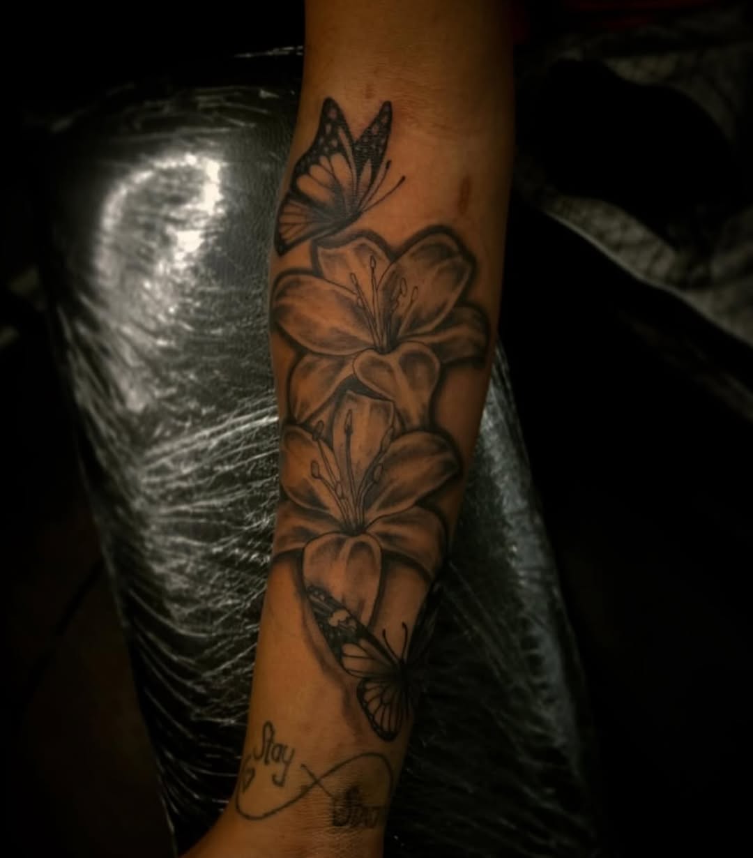 Lilies and butterflies fine line tattoo on the forearm by @tattsbyleek