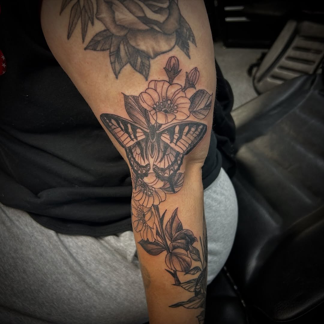 Butterfly and flowers fine line tattoo on the forearm by Gillian