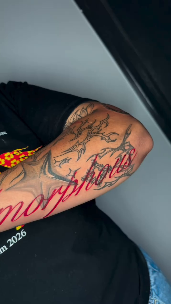 Amorphous lettering with illustrative elements lettering tattoo on the upper arm by 𝕽𝖆𝖈𝖍𝖊𝖑 𝕽𝖆𝖉𝖎𝖈𝖆𝖑 Queens Tattooer