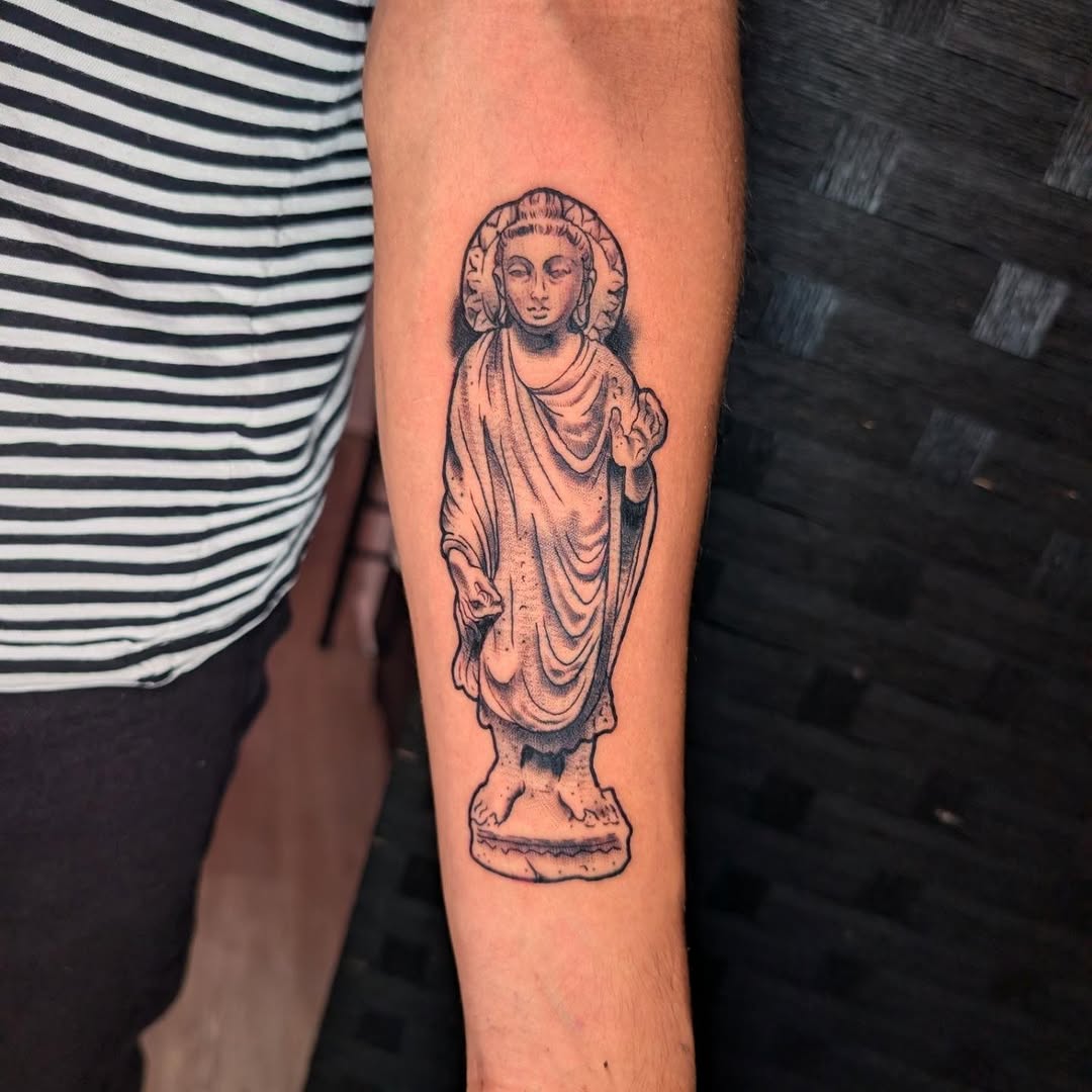 Buddha statue realism tattoo on the forearm by norn noszka
