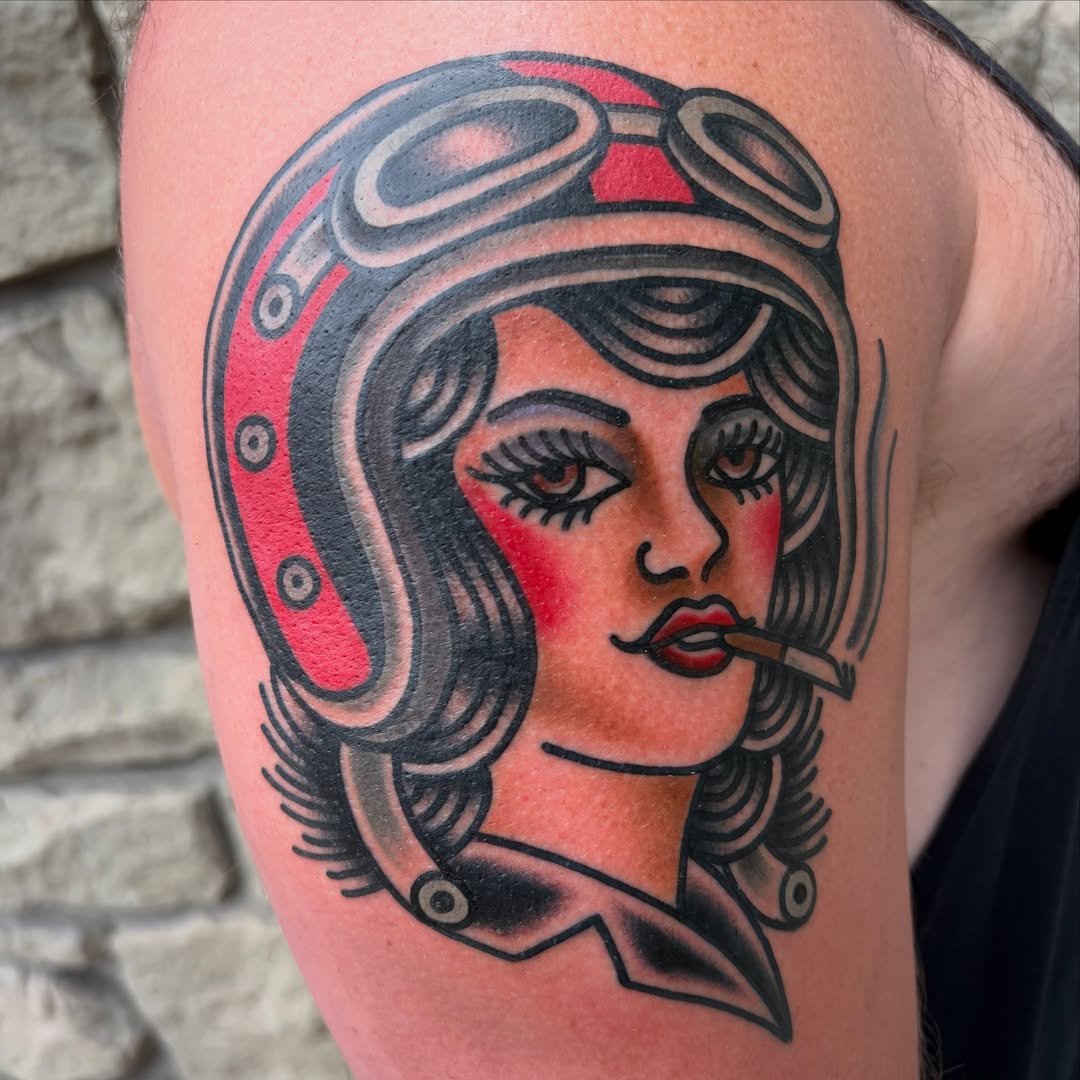 Woman wearing aviator helmet American traditional tattoo on the upper arm by Adrian Godoy