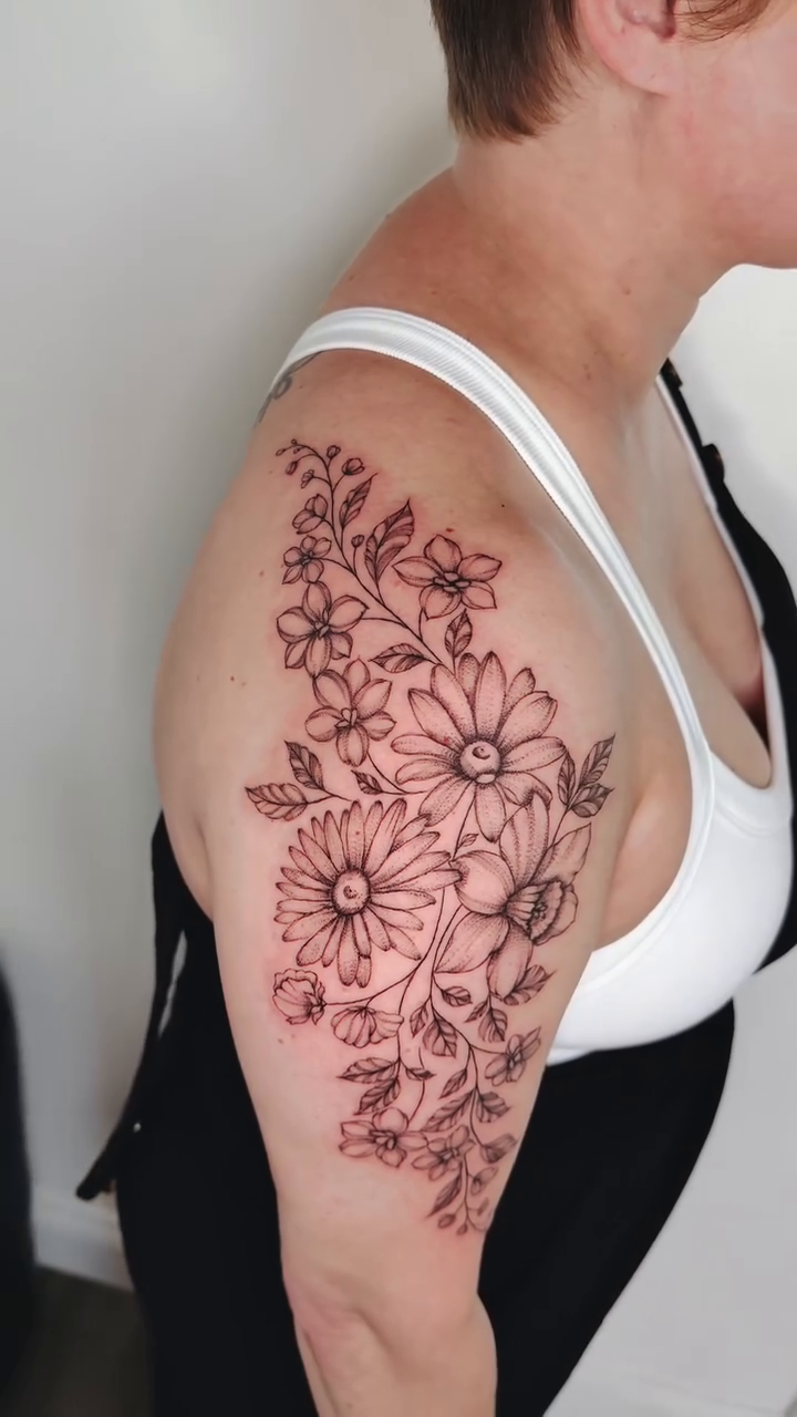 Floral arrangement tattoo on arm ornamental tattoo on the upper arm by Fine Line Tattoo Artist