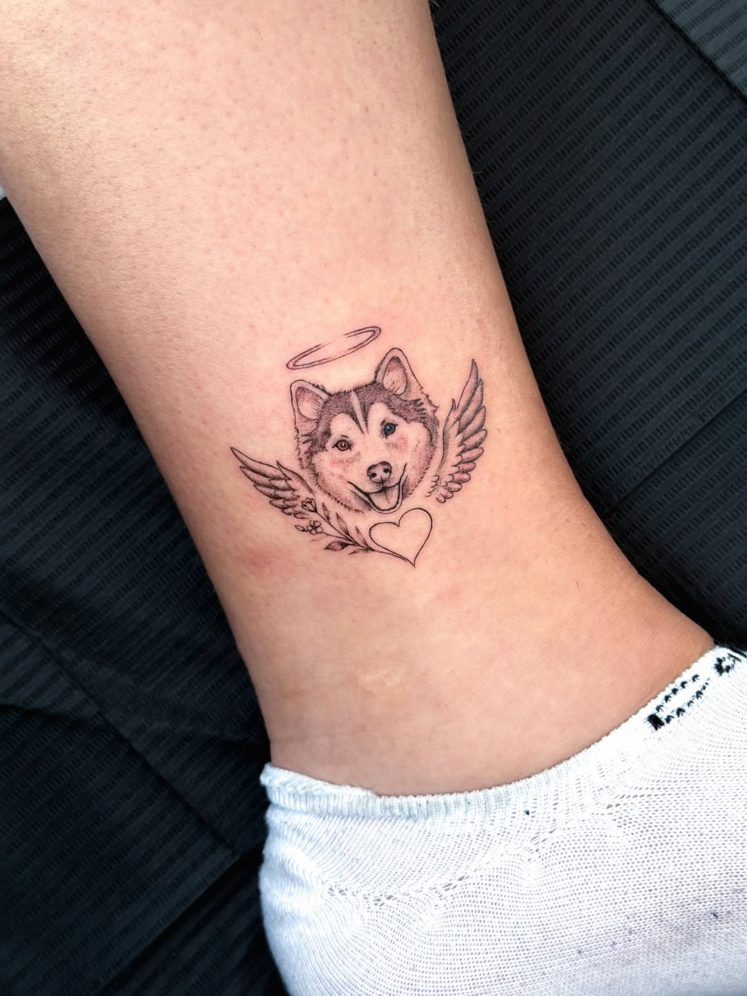 Husky dog with wings and halo realism tattoo on the forearm by Fine Line Tattoo Artist