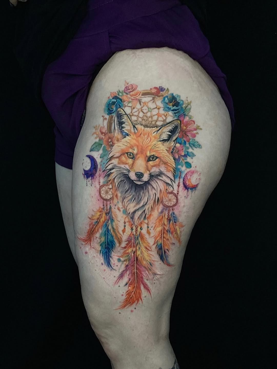 Fox with dreamcatcher and flowers watercolor tattoo on the thigh by Alexey Molyarenko