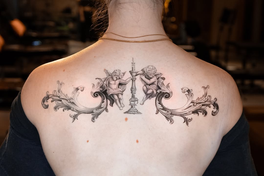 Cherubs with candelabra and baroque scrollwork realism tattoo on the back by Mateo