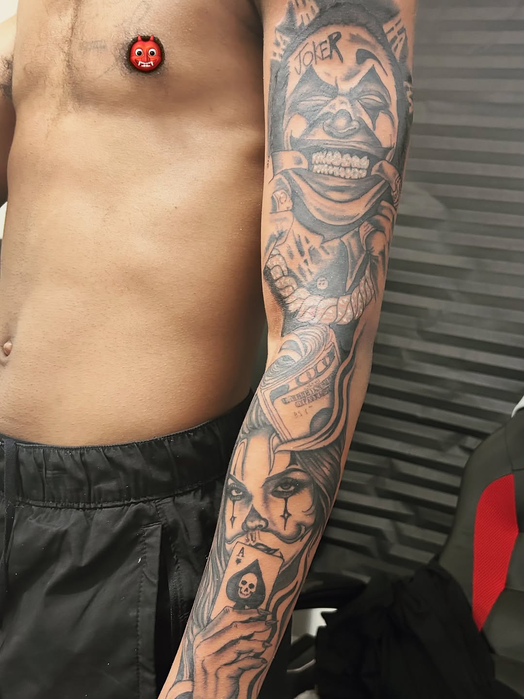 Joker and woman with ace card realism tattoo on the upper arm by @delitotattoos