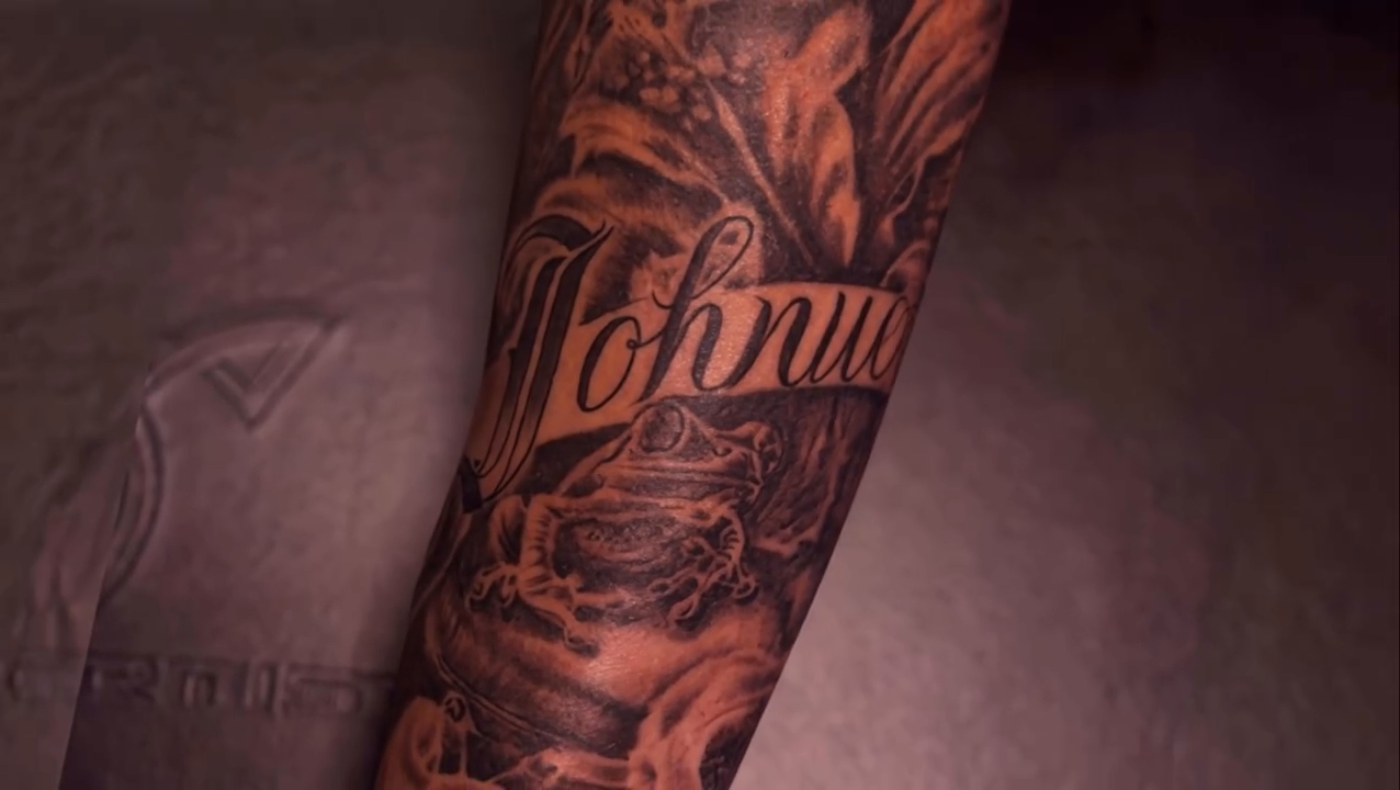 Arm sleeve with lettering and roses Chicano tattoo on the upper arm by Antonio Gordon