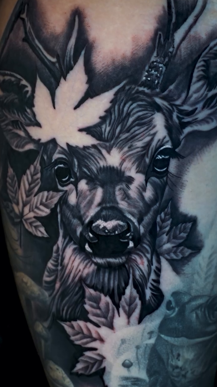 Deer head with leaves realism tattoo on the upper arm by Travis