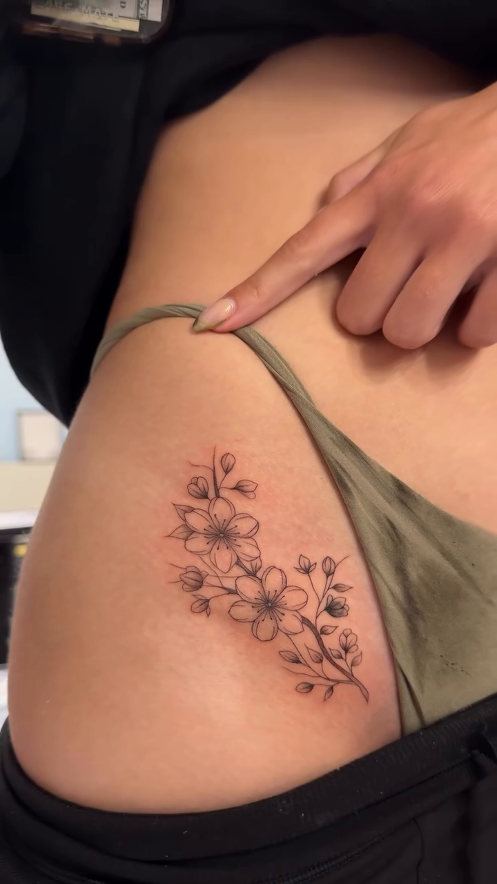 Cherry blossoms with vine fine line tattoo on the thigh by Jennifer Garcia R - Vegas tattoo artist