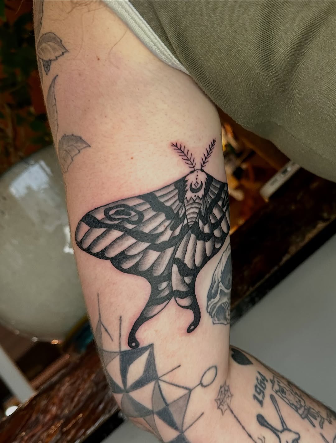 Moth with crescent moon fine line tattoo on the forearm by Jadelin, San Francisco, California